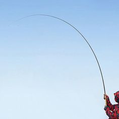 a man flying a kite in the sky with a long pole attached to his back