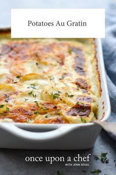 a casserole dish with potatoes, cheese and herbs in it on a table