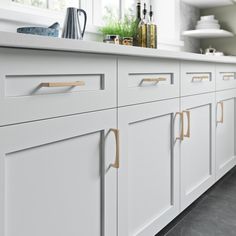 a kitchen with white cabinets and gold handles