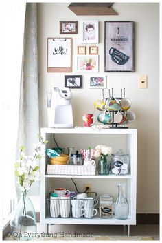 a white shelf filled with lots of items next to a wall covered in framed pictures