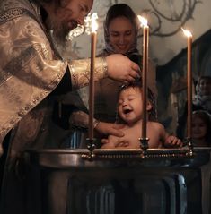 a man and woman standing next to a baby in a bathtub with candles on it