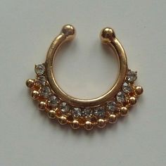 a gold colored nose ring with clear stones