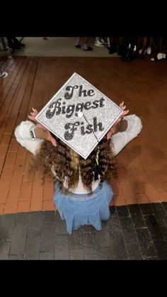 a girl with curly hair holding up a sign that says the biggest fish on it