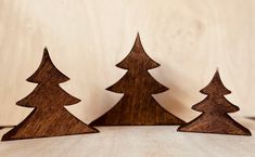 three wooden christmas trees sitting on top of a table