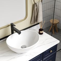 a bathroom sink sitting on top of a white counter next to a wooden stool and mirror