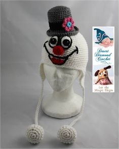 a crocheted hat with a dog's face on it and a book in the background