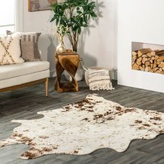 a living room with wood and rugs on the floor next to a fire place