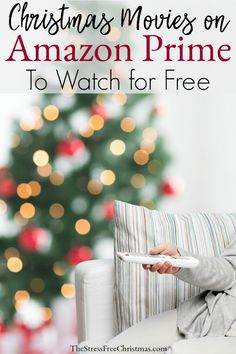 a woman sitting on a couch holding a remote control in front of a christmas tree