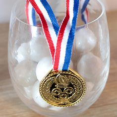 a glass filled with white and blue candies next to a gold medal on top of it