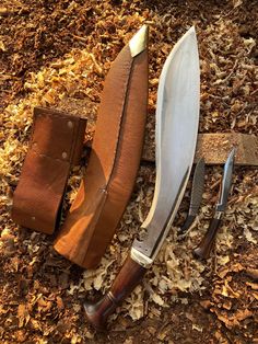 two knives are laying next to each other on the ground with wood shavings around them