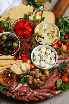 a platter filled with meats, cheeses and other foods on top of a wooden table