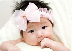 a baby girl with a pink bow on her head