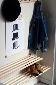 a pair of brown shoes sitting on top of a wooden bench next to a hat rack