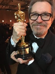 a man in a tuxedo holding an oscar statue