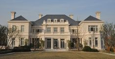 a large white house sitting on top of a lush green field