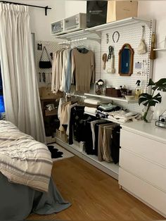 a bedroom with clothes hanging on the wall and a bed next to an open closet