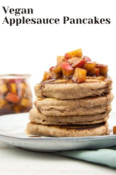 a stack of pancakes topped with apples and cinnamon on a plate next to a jar of maple syrup