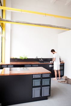 a man standing next to a dog in a room with lots of counter top space