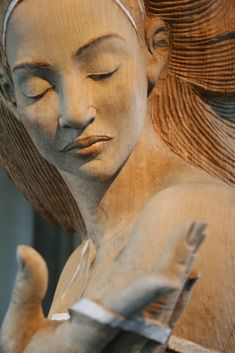 a wooden carving of a woman with her eyes closed and hands folded over her chest