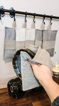 a person holding a cloth in front of a rack with towels