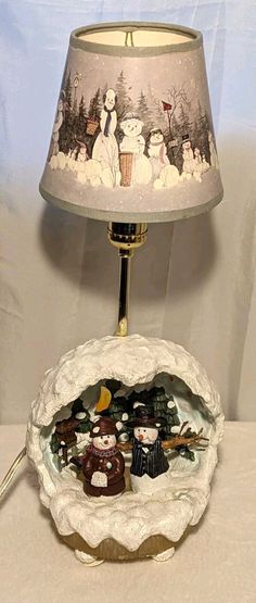 a lamp that is on top of a table next to a bowl with snowmen in it