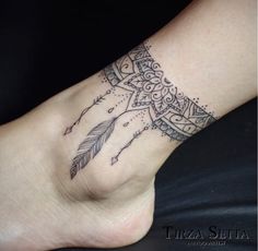 a tattoo on the foot of a woman with an arrow and feathers in her hand