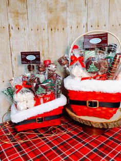 two baskets filled with christmas treats sitting on top of a red and white checkered table cloth