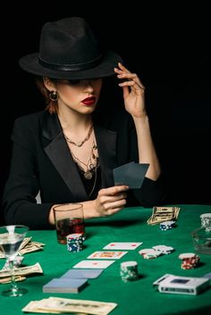 a woman sitting at a table with cards and playing cards in front of her face