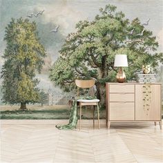 a room with a wall mural and a chair in front of the dresser that has a lamp on it