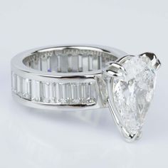 an engagement ring with a pear shaped diamond and baguetts on the side, set in white gold