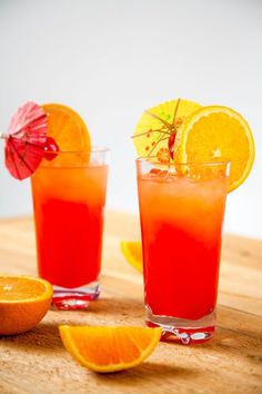 two glasses filled with orange juice and garnished with an umbrella