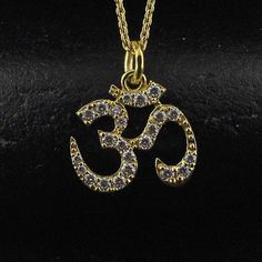 This diamond Om pendant charms with chain, is a beautiful symbol of mindfulness and healing. Adorned with a lotus flower design, it embodies chakra balance and calming energy. Perfect gift for those who embrace Hindu spirituality or seek a meaningful, elegant charm.. Our yoga aum Religious Necklace is not only a fashionable statement of faith but also a symbol of enlightenment, inner peace, and tranquility. Diamond ✦ 𝗡𝗮𝘁𝘂𝗿𝗮𝗹  Diamond - 0.20 ct  - TCW  ( Main Stone )  ✦ Brilliant Round Cut - F/ G / H  ✦ VS / SI ( 1 - 2 ) - eye clean ✦ Excellent / Very Good Cut ✦ Size (mm) : 1.1mm / 1.6mm (approx) ✦ Setting :  𝗣𝗿𝗼𝗻𝗴 + 𝗠𝗶𝗰𝗿𝗼 𝗽𝗮𝘃𝗲  Metal  ✦ Made of recycled 𝗦𝗼𝗹𝗶𝗱 𝗚𝗼𝗹𝗱 - Nickel free  -  ✦ 10k (417) / 14k (585) / 18k (750) - (as per order)    ✦ Color - Yellow, White Spiritual Jewelry With Diamond Accents For Gifts, Spiritual Charm Necklaces For Anniversary, Diamond Necklace For Festivals And Gifts, Diamond Necklaces For Festivals And Gifts, Spiritual White Jewelry For Diwali, Spiritual Gemstone Jewelry For Diwali, Spiritual Pendant Charm Necklaces For Wedding, Spiritual Yellow Gold Necklace For Diwali, Spiritual Round Pendant Necklace For Diwali