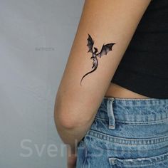 a woman's arm with a small dragon tattoo on the left side of her body