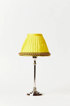 a lamp that is on top of a white surface with a yellow lampshade