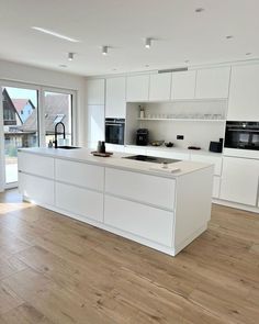 a large kitchen with white cabinets and wood floors