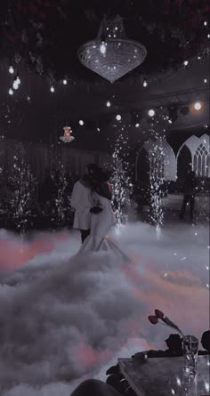 a man and woman standing in the middle of a cloud filled room with chandeliers hanging from the ceiling