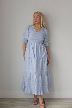 This elegant Blue Smocked Midi Dress features a flattering smocked bodice and flowing tiered midi length design. With a classy v neckline and convenient side pockets, this dress combines style and functionality for any occasion. Stay comfortable and chic in this must-have dress. v-neckline smocked bodice tiered lined side pockets true to size 100% rayon model is wearing a small Chic V-neck Midi Dress With Smocked Cuffs, Blue V-neck Tiered Dress With Ruffle Hem, Modest V-neck Dress With Smocked Back, Blue Midi Dress With Gathered Waist, Elegant Smocked Midi Dress With Ruffle Hem, Elegant Midi Smocked Dress With Ruffle Hem, Elegant Maxi Dress With V-neck And Smocked Cuffs, Spring Blue Maxi Dress With Gathered Waist, Blue Smocked Dress With Ruffles And Tiered Skirt