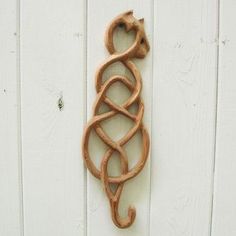 a decorative wooden hook on the side of a white wall with a cat in it's mouth