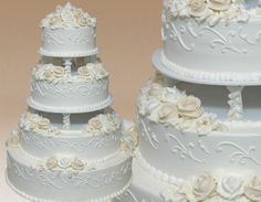 three tiered wedding cake with white flowers on each layer and an intricately decorated topper