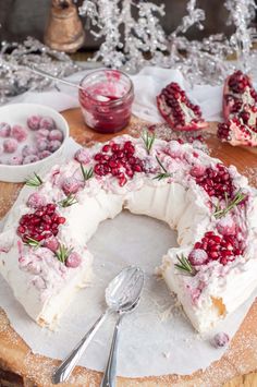 a cake with cranberries on it sitting on top of a cutting board next to other desserts