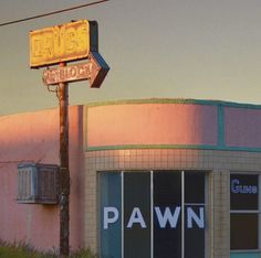 an old pawn store with the sun setting on it's roof and sign in front