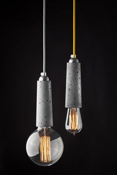 two light bulbs hanging from a ceiling fixture in a dark room with the lights turned on