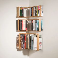 three wooden shelves with books on them against a wall