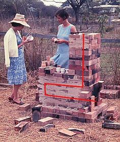 two women standing next to a pile of bricks