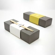 two boxes with chopsticks in them sitting next to each other on a white surface