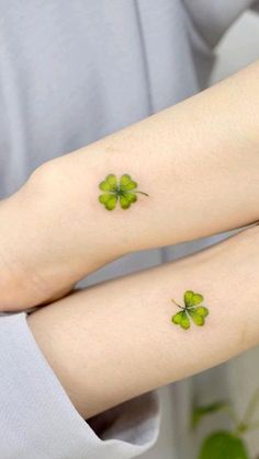 two people with green shamrock tattoos on their legs, one is holding the other's arm