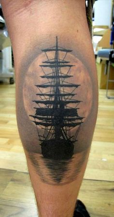 a man's leg with a black and white tattoo of a ship on it