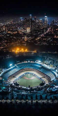 an aerial view of a baseball stadium at night with the city lights in the background