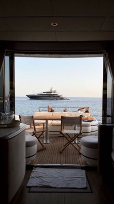 an open door leading to a large boat in the ocean with chairs and tables on it