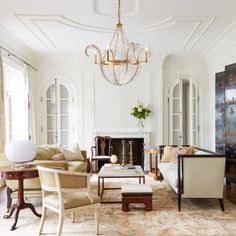 a living room filled with lots of furniture and a chandelier hanging from the ceiling